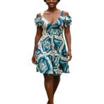 Woman wearing blue and teal Ikat print cold shoulder mini dress with V-neck and ruffles. Tropical A-line summer sundress