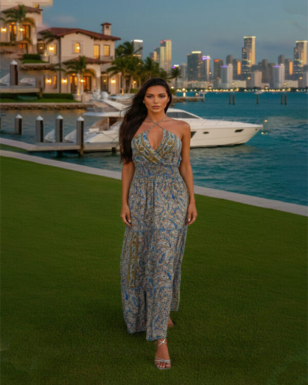 Woman with curly hair wearing a blue paisley tiered boho maxi dress with a V-neck and smocked waist