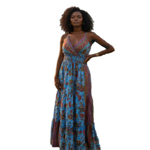 Woman with curly hair wearing a blue paisley tiered boho maxi dress with a V-neck and smocked waist, posing against a white background