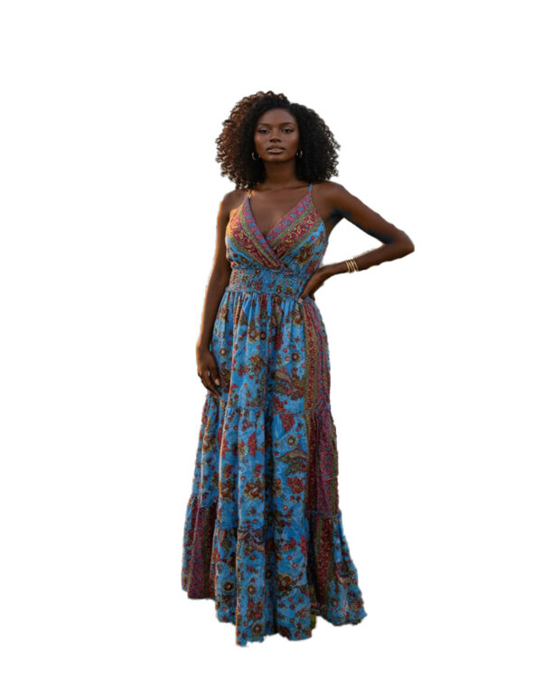 Woman with curly hair wearing a blue paisley tiered boho maxi dress with a V-neck and smocked waist, posing against a white background