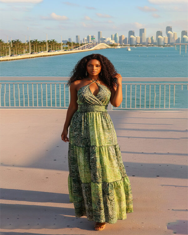 Woman with curly hair wearing a blue paisley tiered boho maxi dress with a V-neck and smocked waist