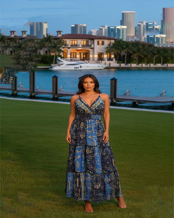 Woman with curly hair wearing a blue paisley tiered boho maxi dress with a V-neck and smocked waist